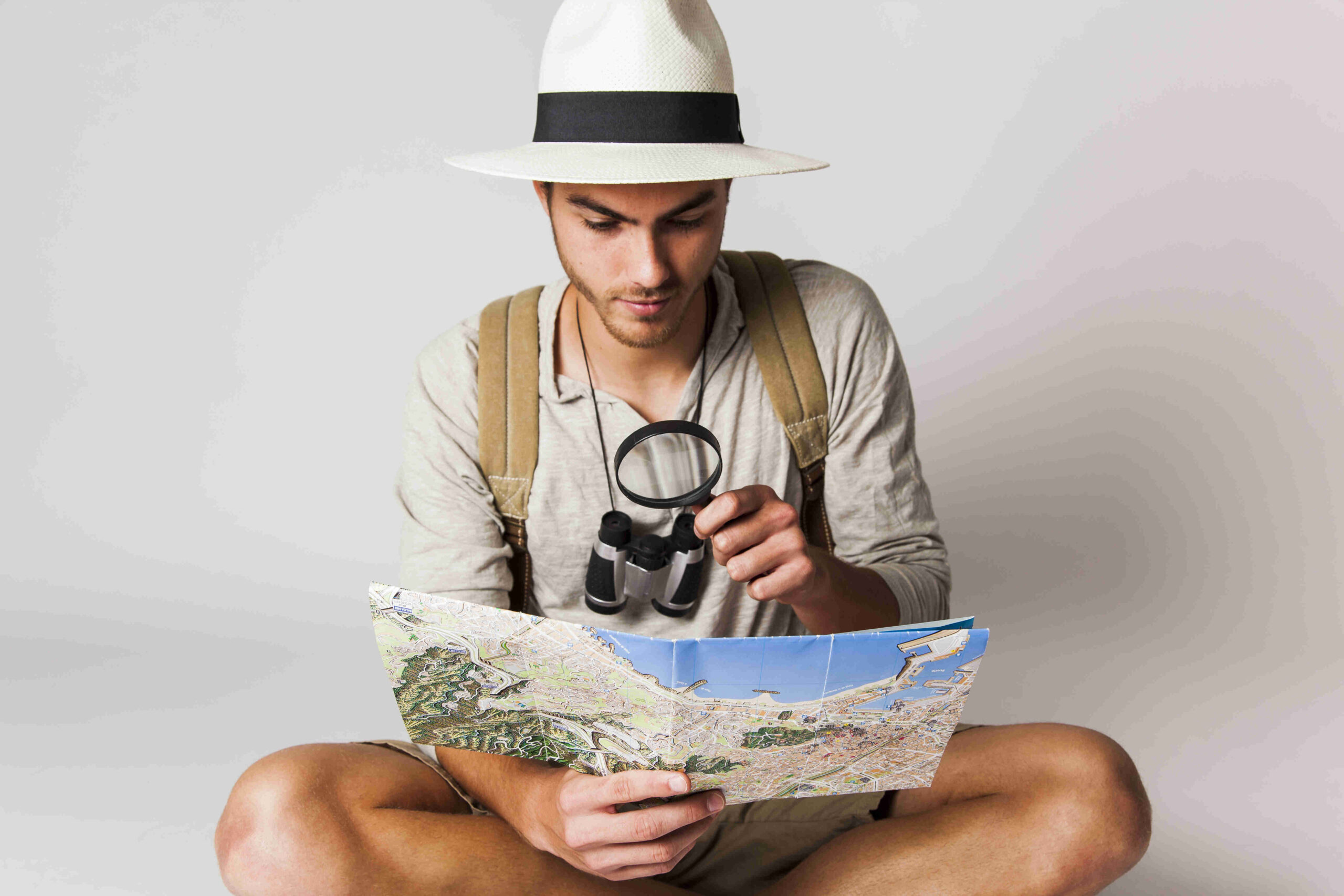 sitting-tourist-looking-map-with-magnifying-glass_compressed